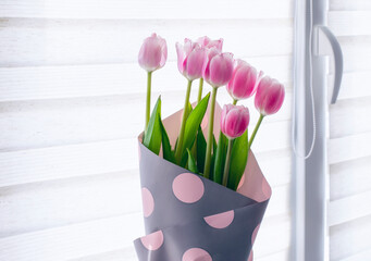 Bouquet of pink tulips near the window.