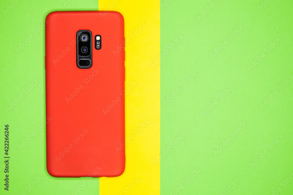 Aufkleber top view of red mobile phone case isolated on green and yellow background with copy space