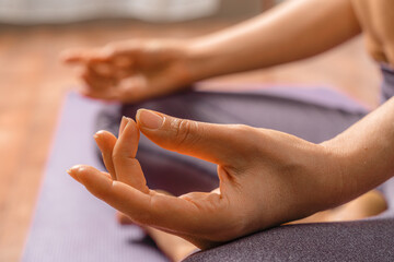 Young woman meditating in the lotus pose at home. Practicing yoga indoors. Harmony, yoga practice, balance, meditation, relaxation at home, healthy lifestyle concept.