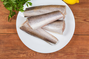 Top view of raw hake on dish on rustic table