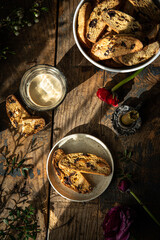 Homemade almond and chocolate biscotti with glass of coffee and  ranunculus flowers on wooden table...