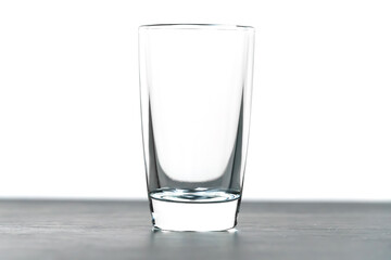 Close-up of a standing empty shot glass on a black table on a white background with copy space, macro