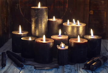 Still life with group of black burning candles on witch table.