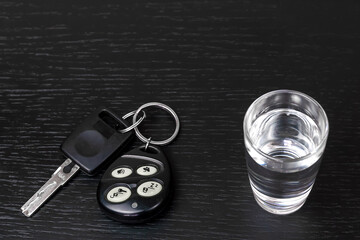 On the black table are the car keys and a shot of vodka close-up with copy space. Concept of drunk driving