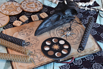 Still life with witch diary with wiccan symbols, candles, wooden circle with moon phases.
