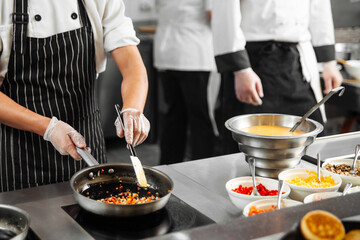 Restaurant cooks preparing food in the kitchen with vegetables