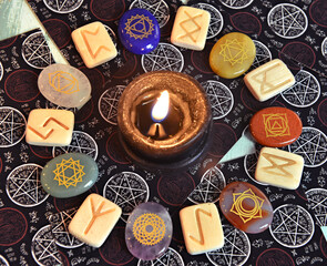 Still life with runes and chakra crystal stones with burning candle and tarot cards.