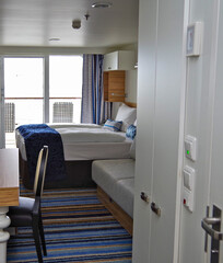 Modern interior design balcony or verandah cabin stateroom with double queen bed, couch, vanity...