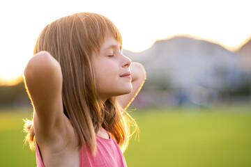 Portrait of young pretty child girl relaxing outdoors on warm summer day.