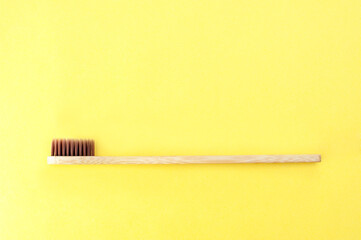 Bamboo toothbrush on a yellow background. Top view, space for text. 