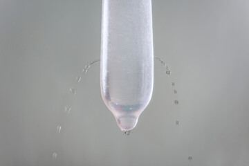 Water is leaked from a condom full of holes.Danger of sexual disease.