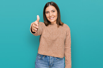 Young beautiful woman wearing casual clothes smiling friendly offering handshake as greeting and welcoming. successful business.