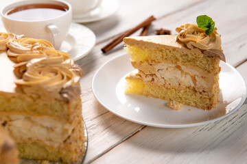 A piece of cake on a plate on a white wooden background