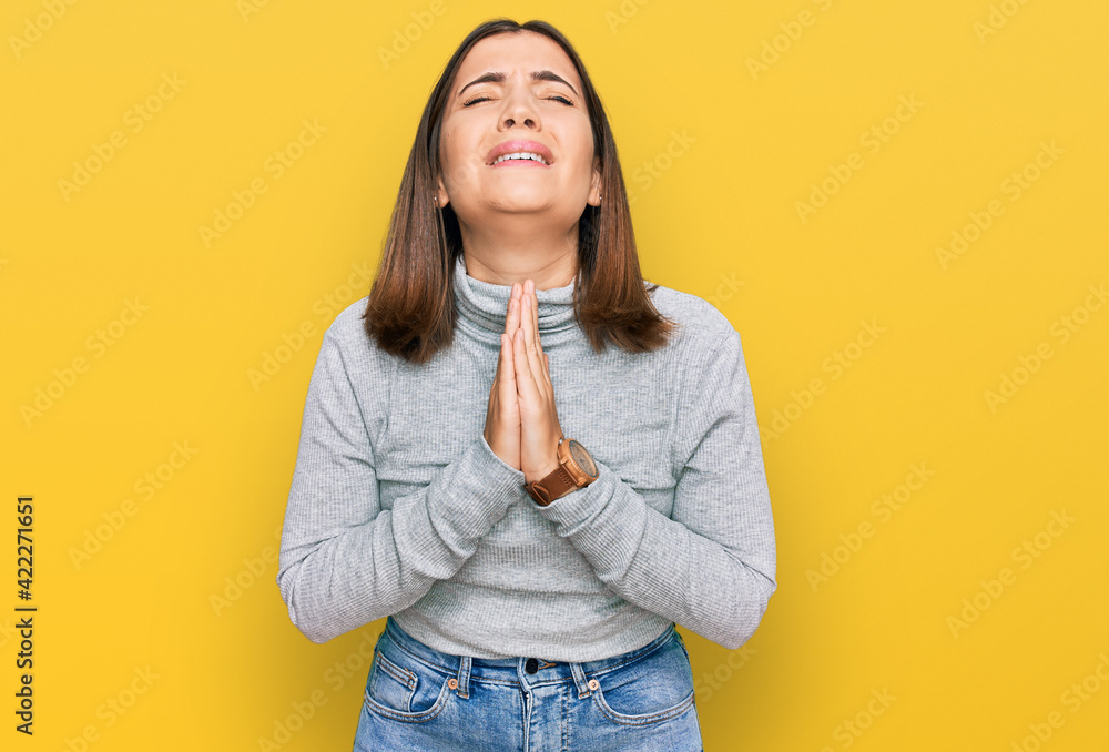 Sticker young beautiful woman wearing casual turtleneck sweater begging and praying with hands together with