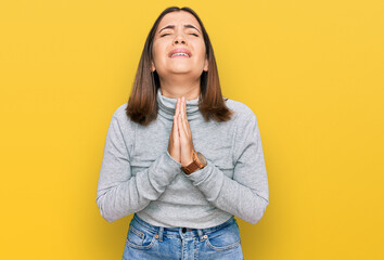 Young beautiful woman wearing casual turtleneck sweater begging and praying with hands together with hope expression on face very emotional and worried. begging.