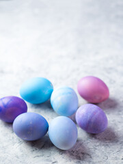 Colorful pastel-colored Easter eggs on a white stone table copy space