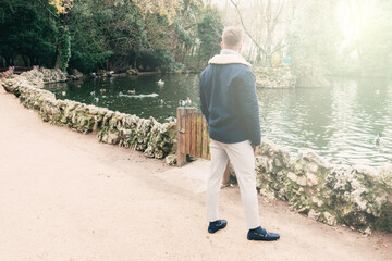 back view of a handsome young blond by a lake