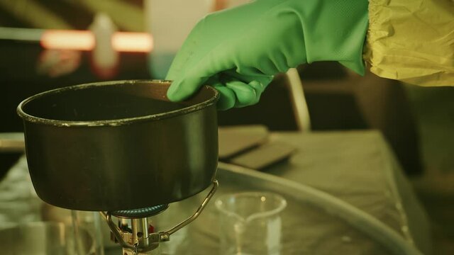 Illegal chemist cooks drugs in underground laboratory wearing mask and works with toxic chemical compounds