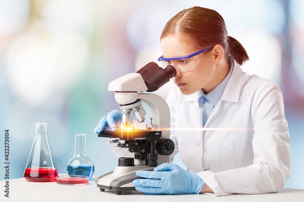 Poster scientist in mask and glasses working with microscope