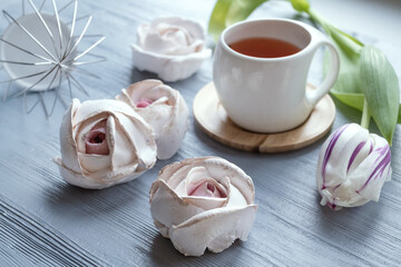 Morning concept. Cup of tea, marshmallow, tulip. White cup with tea, pink tulips and marshmallows.