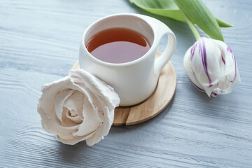 Morning concept. Cup of tea, marshmallow, tulip. White cup with tea, pink tulips and marshmallows.