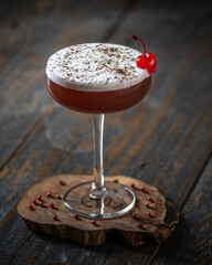 cocktail rosso in coppa con ciliegia al maraschino e pepe rosa