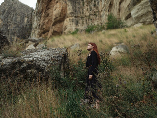 Fototapeta premium A woman in a black dress are walking in the mountains on nature in autumn