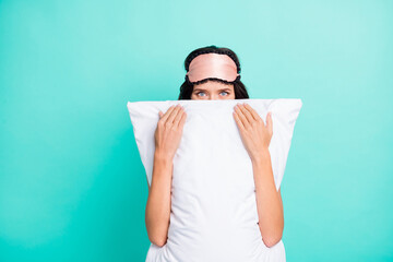 Photo of tricky funny young lady nightwear hiding behind big white pillow isolated teal color...