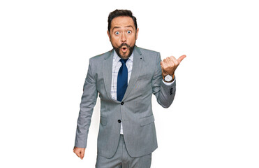 Middle age man wearing business clothes surprised pointing with hand finger to the side, open mouth amazed expression.
