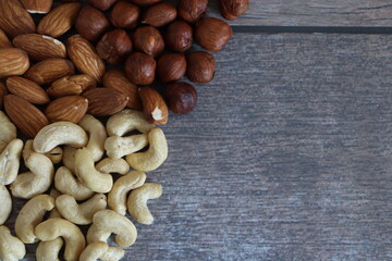 Cashew hazelnuts and almonds on wooden background with space for text