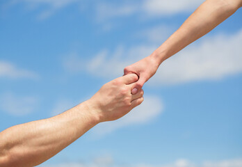 Lending a helping hand. Hands of man and woman reaching to each other, support. Solidarity, compassion, and charity, rescue. Giving a helping hand. Hands of man and woman on blue sky background