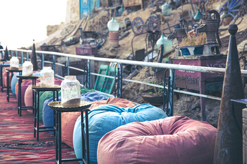 An authentic outdoor cafe with colorful bean bags and antiques.
