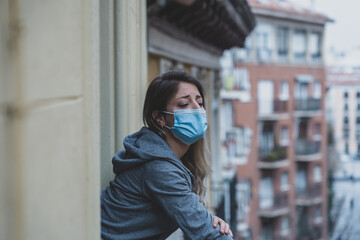 Fototapeta premium Young beautiful unhappy woman with face mask suffering from depression due to isolation