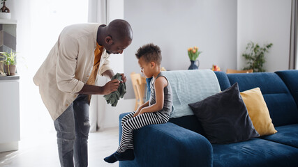 Father with small son getting dressed at home, multi ethnic family.