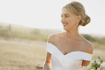 Portrait of a beautiful blonde bride in a white dress with bare shoulders