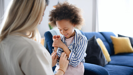 Mother with small daughter getting dressed at home, multi ethnic family.