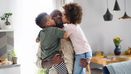 Small children kissing father at home, multi ethnic family. - obrazy, fototapety, plakaty