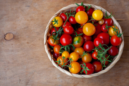 Red and yellow cherry tomatoes bowl top view. Harvest vegetables. Tomato on the table. Vitamin healthy food. Rustic wooden background, copy space - Powered by Adobe