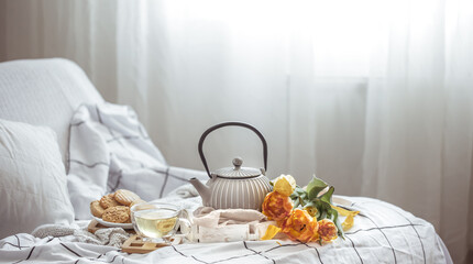Home composition with tea, teapot, cookies and a bouquet of flowers copy space.