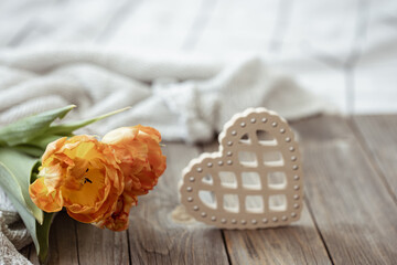 Spring home composition with a bouquet of tulips and a decorative heart on a wooden surface.