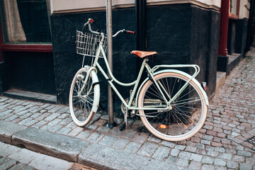 Naklejka na ściany i meble Green bicycle parked on city street. Bicycle parked on footpath