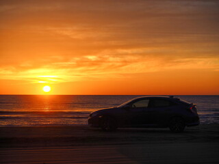 海へ沈む夕日と車