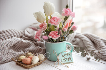 Easter floral arrangement with natural flowers and the inscription Happy Easter on the card.