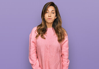 Fototapeta premium Young hispanic woman wearing casual clothes puffing cheeks with funny face. mouth inflated with air, crazy expression.