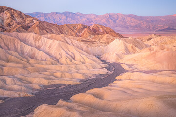 Sunset or sunrise view of Zabriskie Point and the rugged sedimentary rock terrain of the badlands landscape in Death Valley Park National Park, USA.