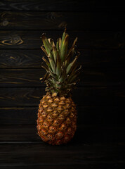 Delicious pineapple (Ananas) on a black wooden background