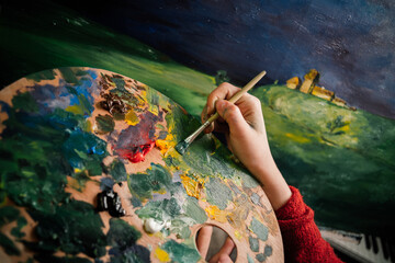 woman paints a picture with paints artist easel palette Bright colors