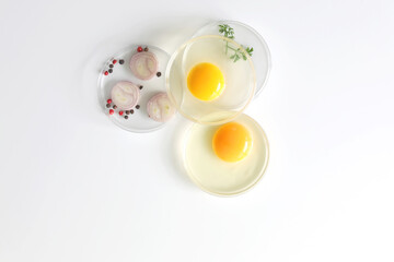 Raw eggs in glass bowls with shallot and pepper on white table. Preparation of omelet. Copy space. Flat lay.