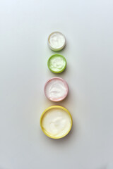 multi-colored jars with white cosmetic cream for face