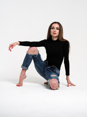 The brunette on a white background in a bodysuit and jeans with heels